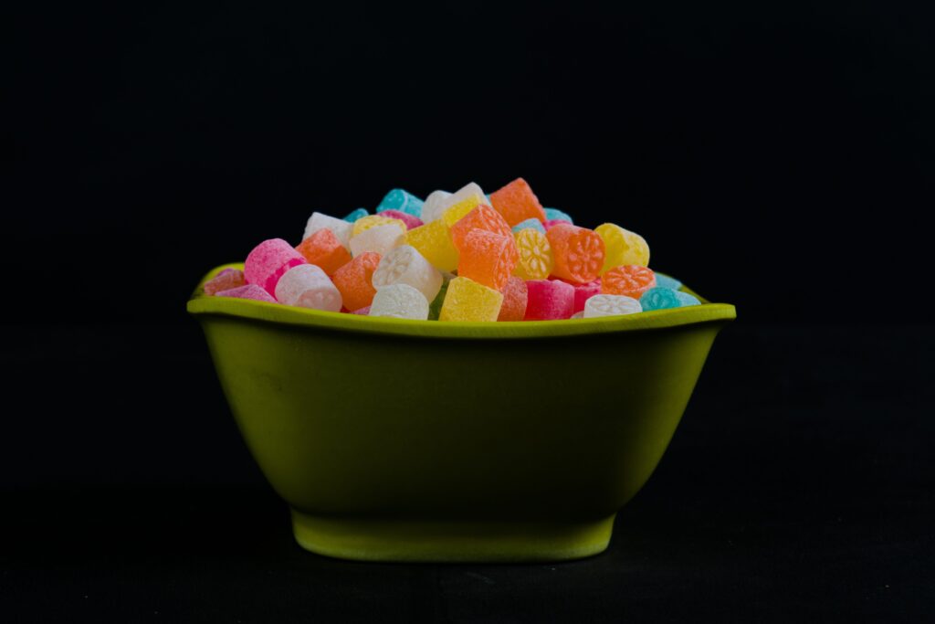 pexels-photo-2231611-2231611 Vibrant gummy candies in a green bowl against a dark backdrop, capturing indulgent sweetness.
