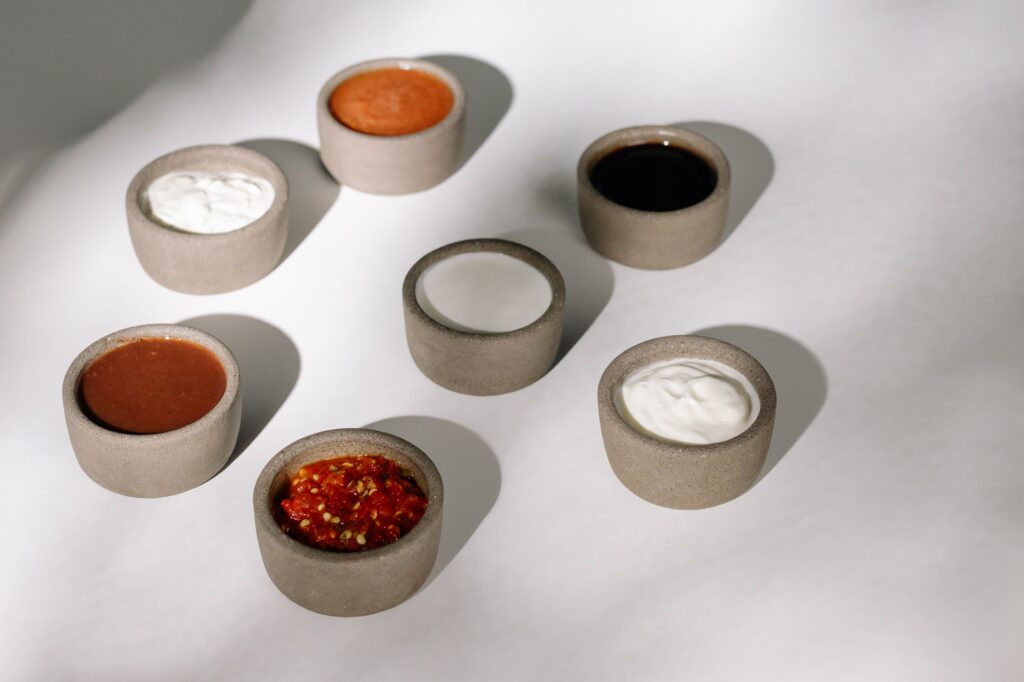 pexels-photo-5899677-5899677-2 Variety of sauces and dips in rustic ceramic bowls under natural sunlight.