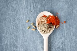 Photo by Kim van Vuuren A collection of vibrant spices displayed on a wooden spoon against a textured background.